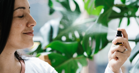 A woman spraying Soothing Facial Mist Natural Skincare with a plant background