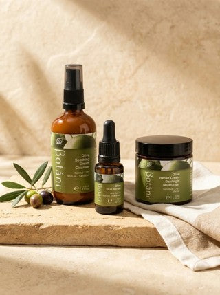 Alt text (for upload): Botani Olive Soothing Cream Cleanser, Olive Skin Serum and Olive Repair Cream grouped together on a warm stone surface with fresh olives and natural linen — a simple three-step sensitive skin routine