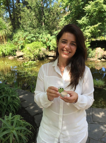 Barbara Filokostas, Naturopath and founder of Botani Skincare Australia, holding the Healing Lip Balm in a botanical garden setting