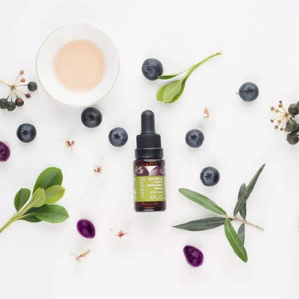 flatlay of ACAI BERRY ACTIVE ANTIOXIDANT SERUM WITH BERRIES AND PINK ACAI BERRY OIL IN A DISH